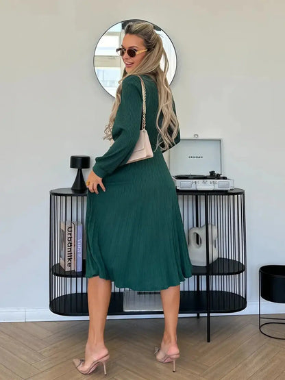 Model showcasing the Emerald Poise Midi Dress in a rich green color, styled with sunglasses and a chic handbag.