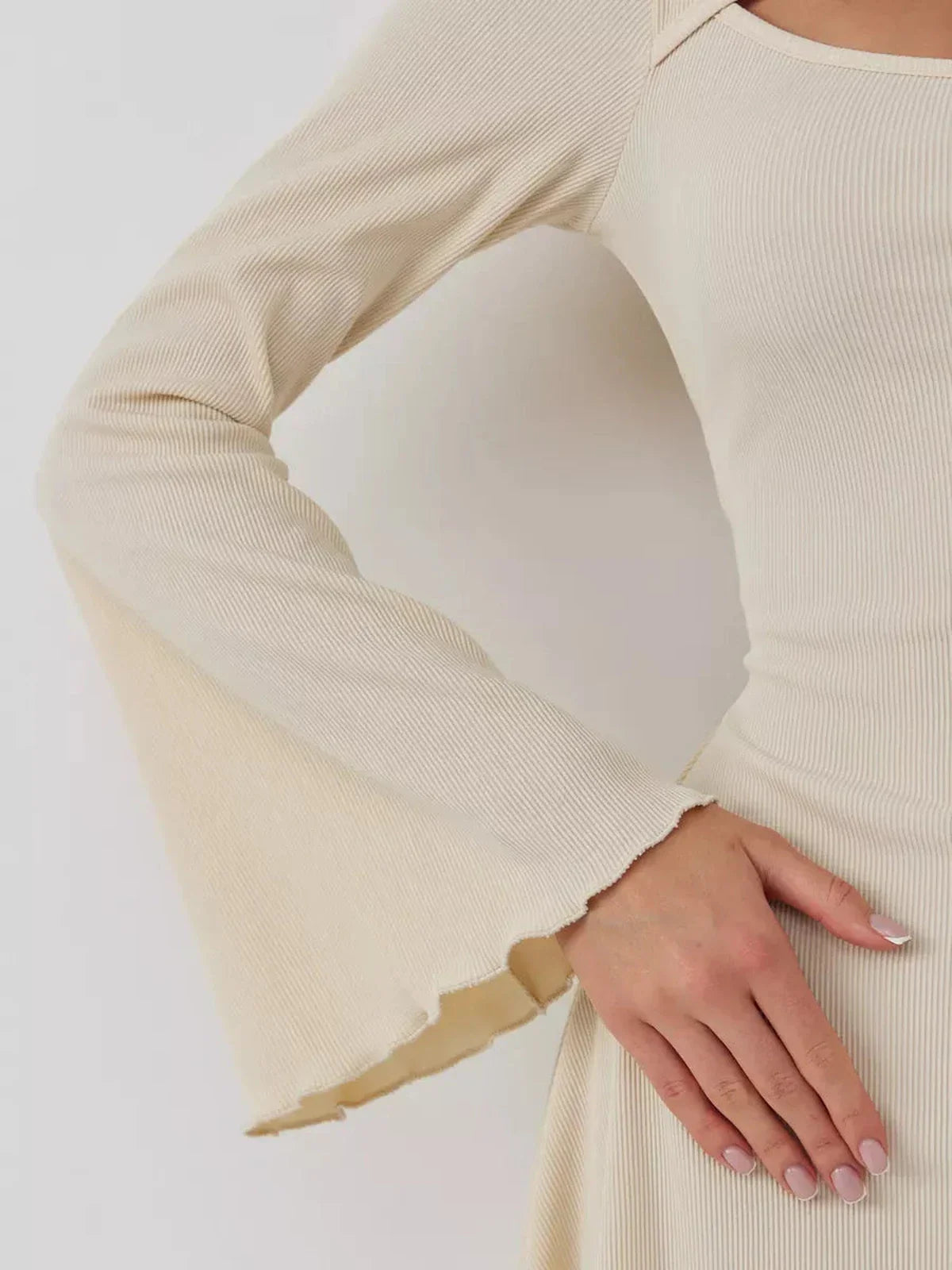 Close-up of a woman's arm showcasing the flared sleeve design of the Sculpted Grace mini dress.