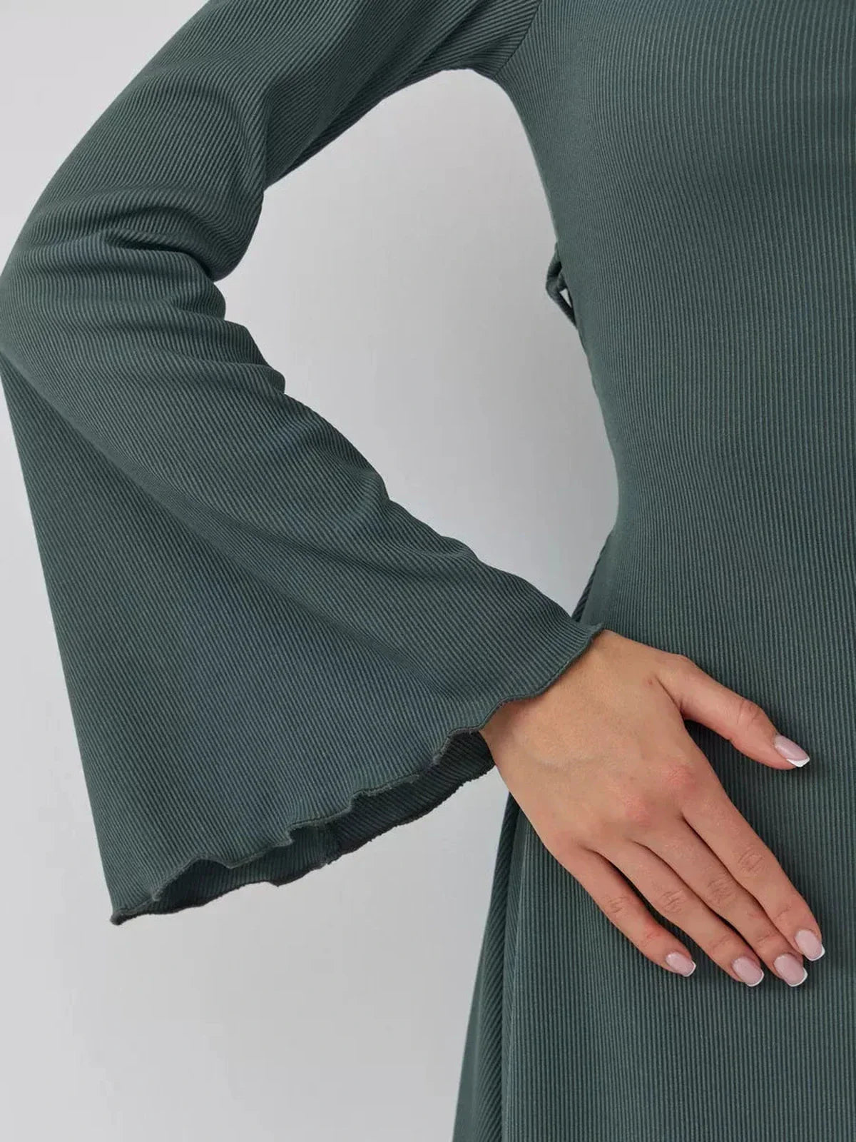 Close-up of a hand resting on a dark olive mini dress featuring dramatic bell sleeves and a soft texture.