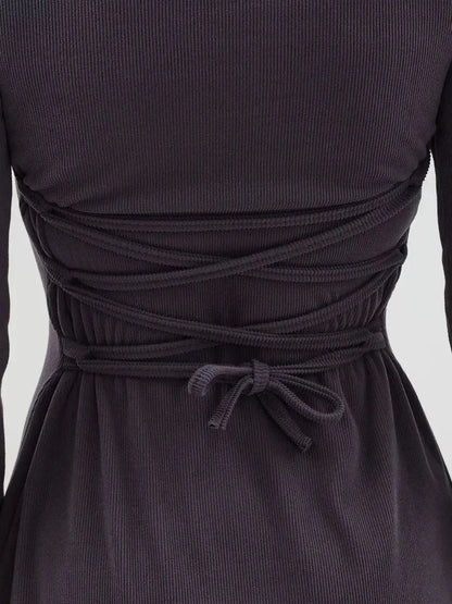 Back detail of the Graphite Charm Mini Dress featuring lace-up tie-back, showcasing its adjustable fit and flared sleeves.
