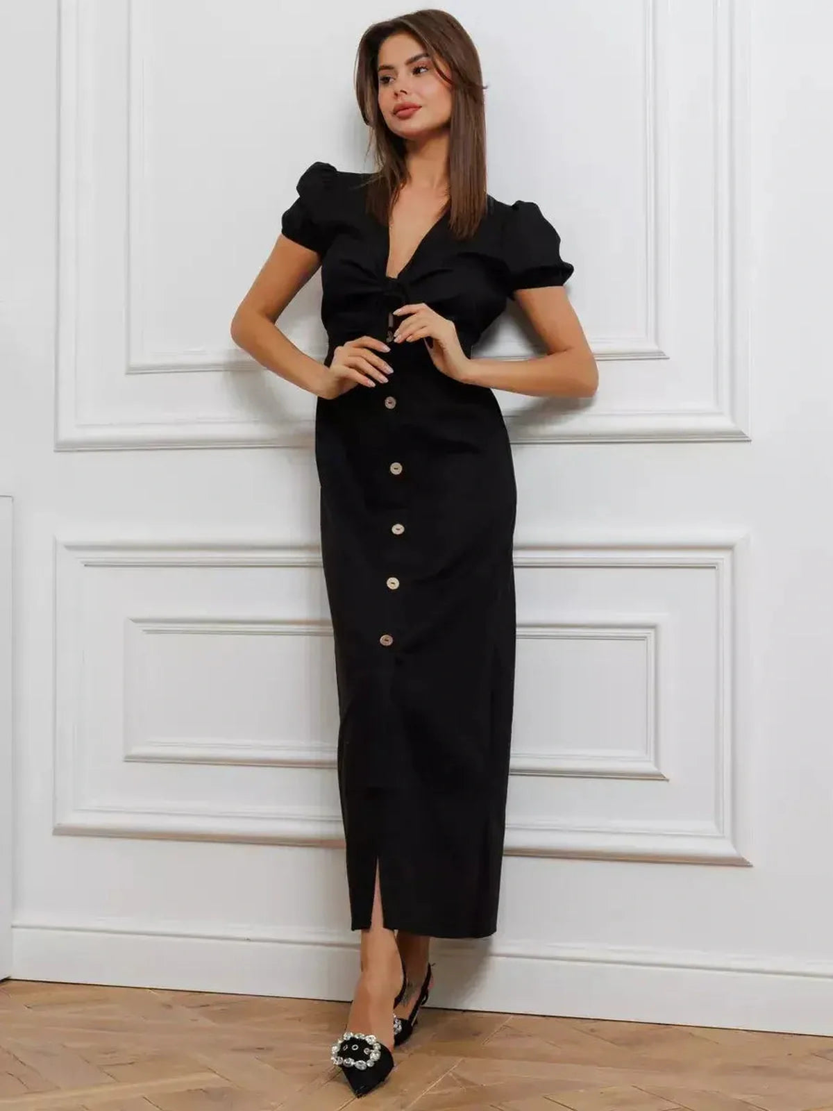 Elegant black maxi dress with puff sleeves and front tie detail, featuring a flattering V-neckline and buttons.