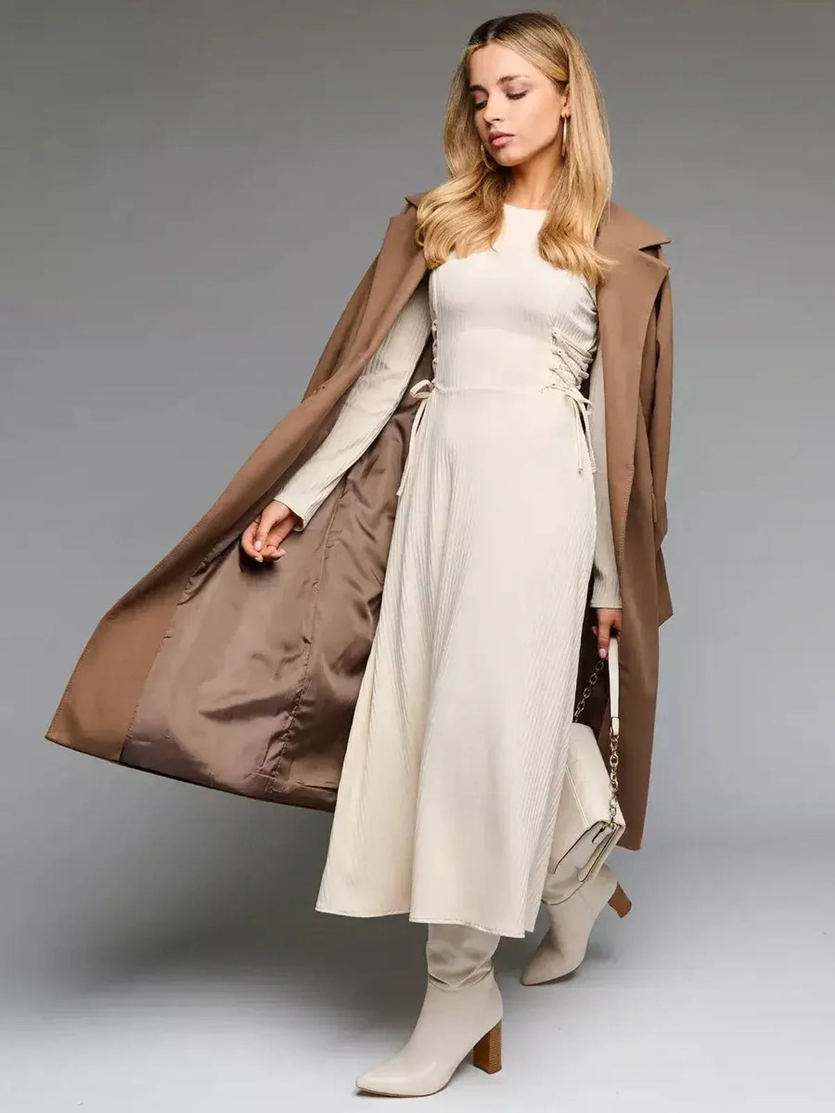 Elegant woman wearing a ribbed midi dress with side lacing, complemented by a stylish coat and boots for a chic look.