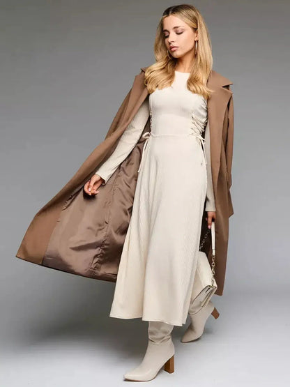 Elegant woman wearing a ribbed midi dress with side lacing, complemented by a stylish coat and boots for a chic look.