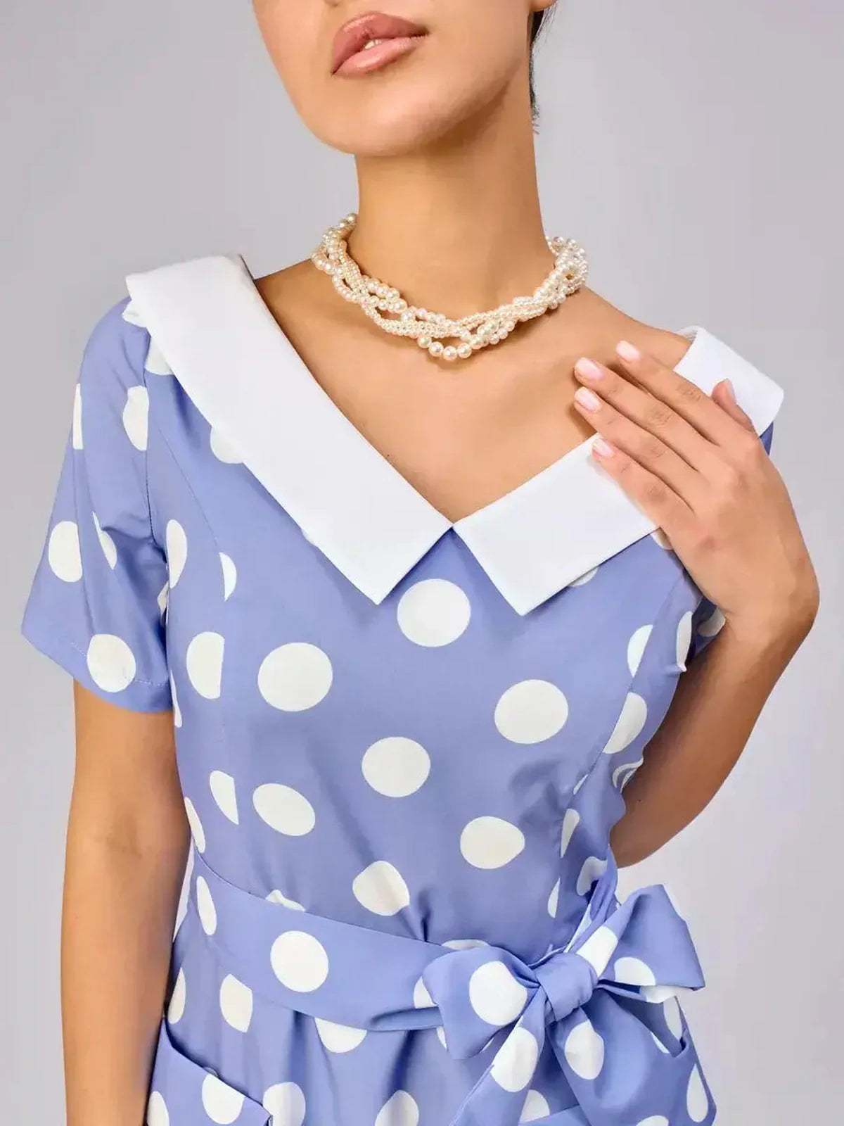 Close-up of woman in Riviera Charm midi dress featuring white polka dots and a contrast collar, exuding summer elegance.