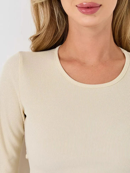 Close-up of a woman's neckline in a ribbed ivory long sleeve dress, showcasing its elegant texture and fit.
