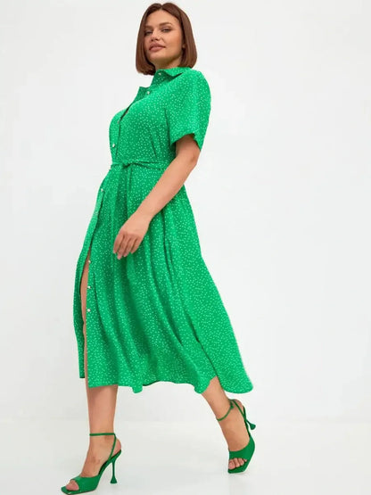 Model showcasing the Garden Dot Midi Dress in vibrant green with white dots, perfect for summer or wedding guest attire.
