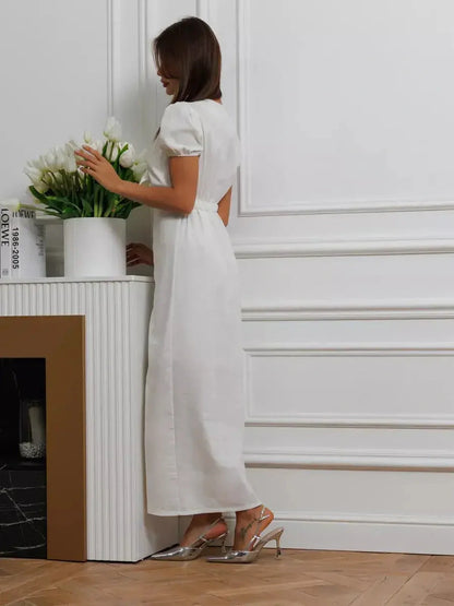 Elegant woman in a white maxi dress with puff sleeves, showcasing minimalist sophistication and a flattering silhouette.