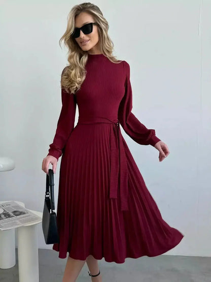 Elegant woman in a crimson midi dress with pleats, sunglasses, and a stylish bag, perfect for formal occasions.