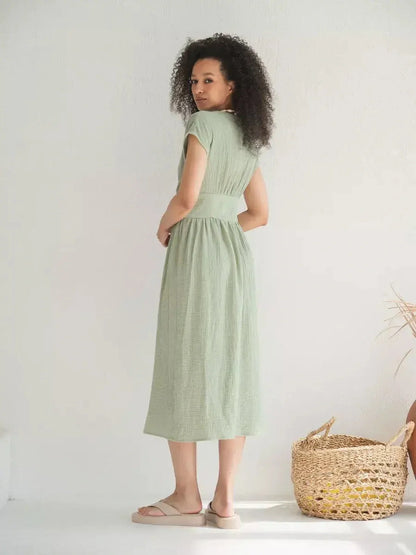 Model wearing a khaki Verdana Midi Dress featuring short sleeves and a flattering corset-inspired waist, perfect for summer occasions.
