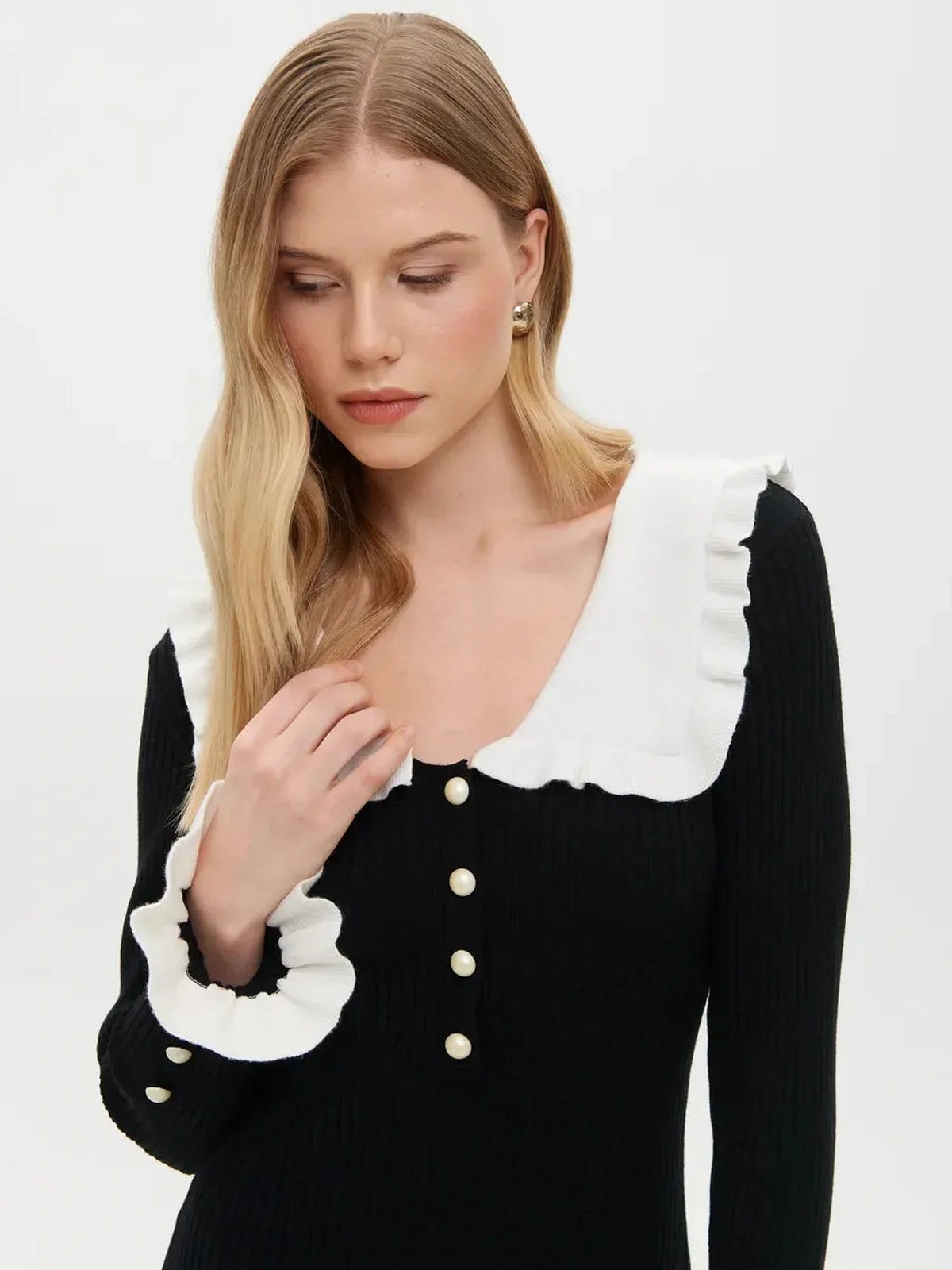 Elegant woman wearing a black ruffle collar midi dress with pearl details and ribbed texture, ideal for weddings and events.