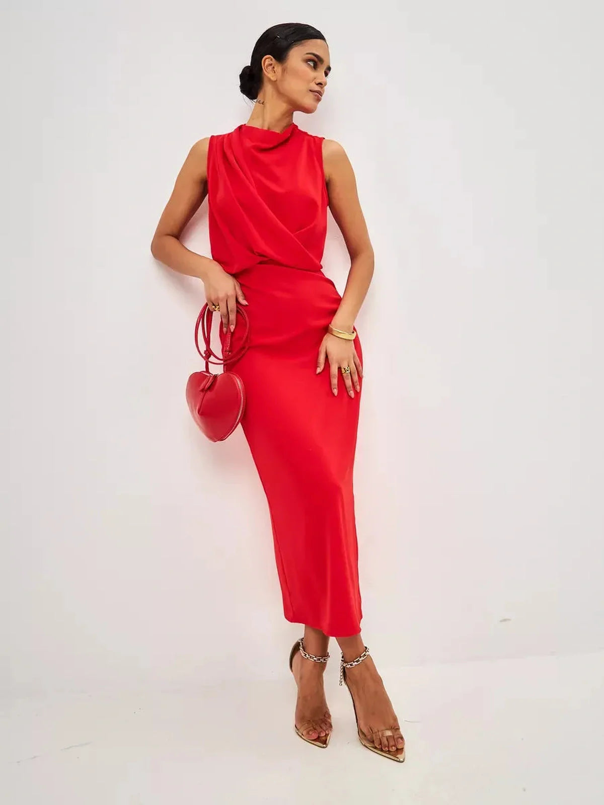 Elegant woman wearing a red drape maxi dress, paired with a heart-shaped handbag and stylish heels, perfect for formal occasions.