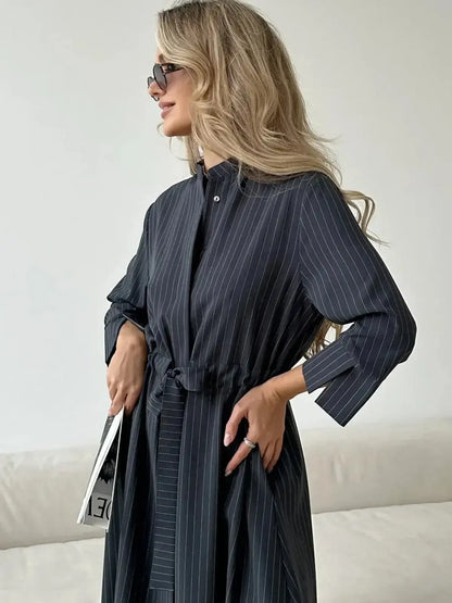 Model showcasing a stylish Slate Stripe Midi Dress with a relaxed fit and vertical pinstripes, perfect for various occasions.