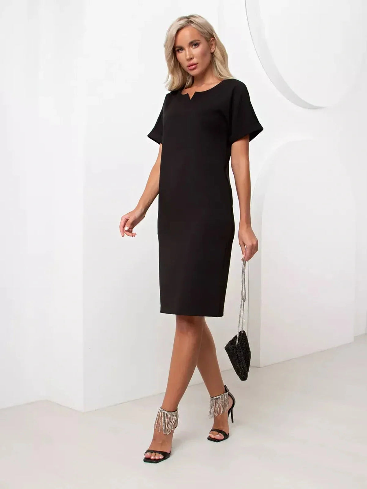 Model wearing the Modern Grace black mini dress with relaxed fit and short cuffed sleeves.