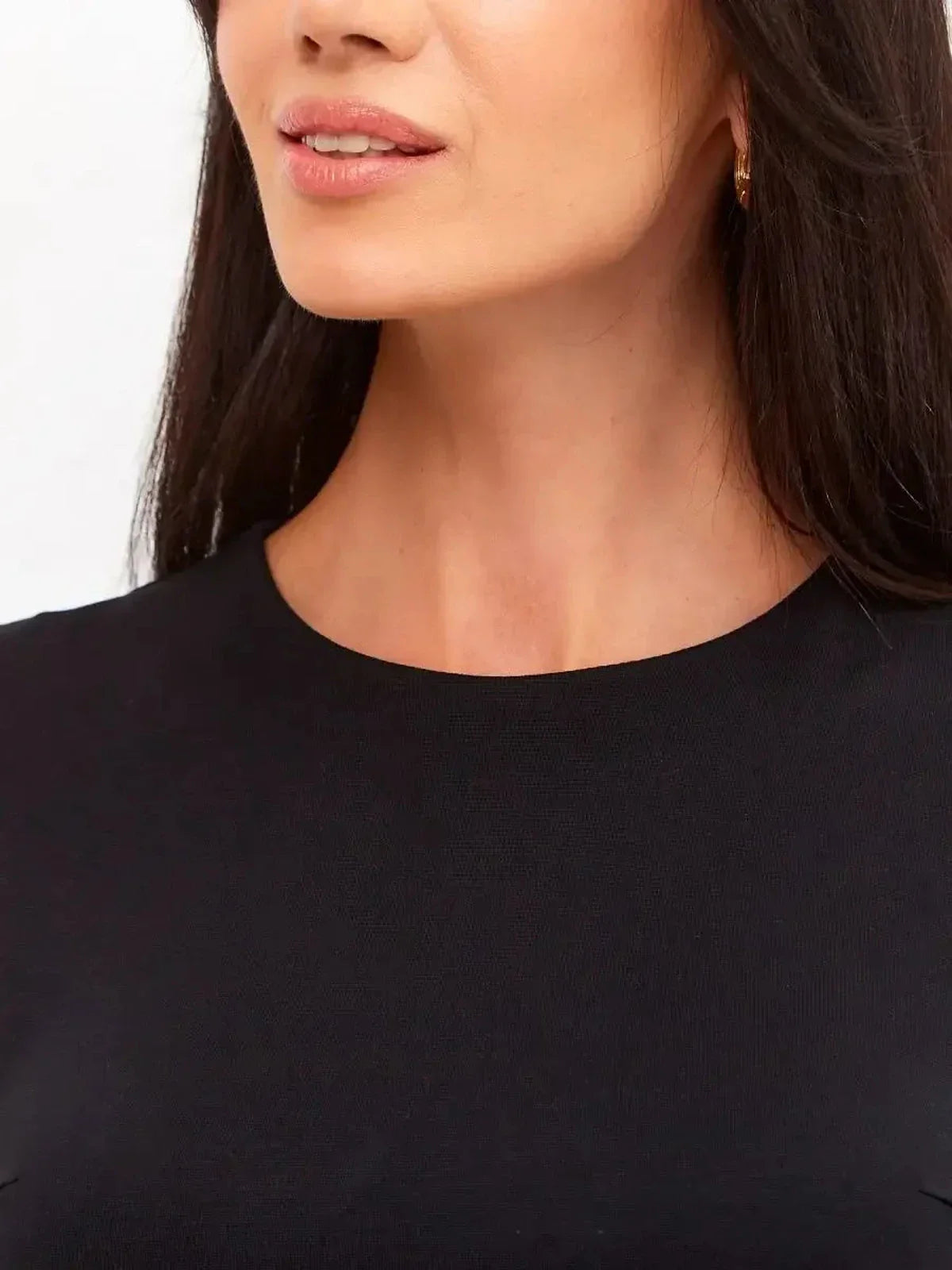 Close-up of a model wearing a sleek black dress, showcasing its elegant neckline and minimalist design.