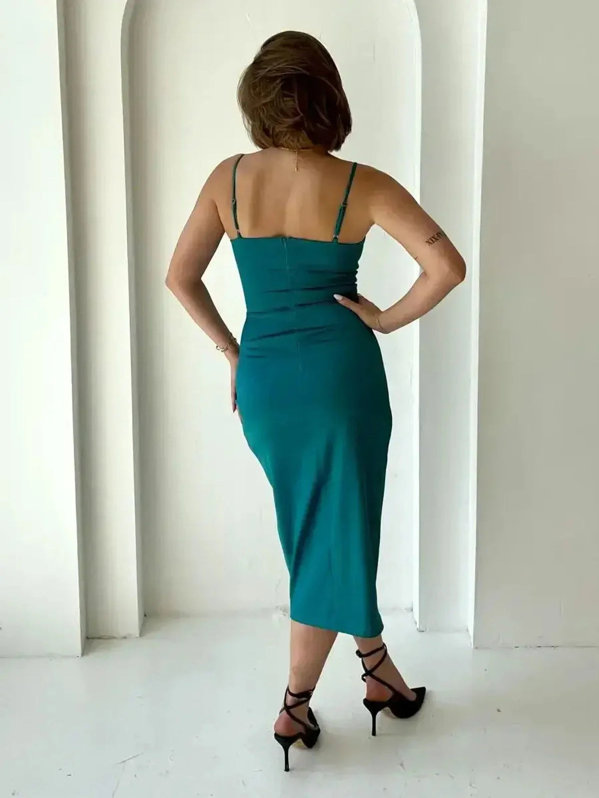 Back view of the Lustre Midi Dress in emerald green, showcasing its sleek satin wrap and elegant silhouette.