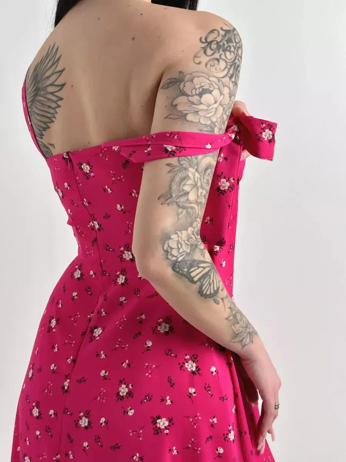 Stylish woman showcasing the Rosé Charm Midi Dress with floral print and shoulder ties, perfect for summer events.
