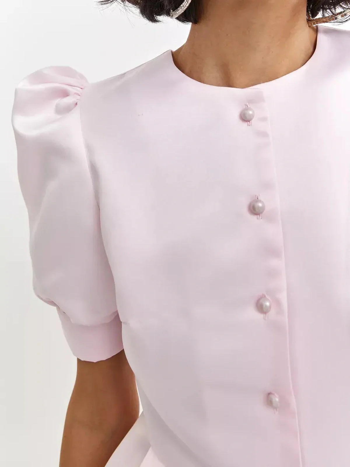 Close-up of the Pearl Puff Mini Dress featuring satin fabric, pearl buttons, and voluminous puff sleeves in soft pink.