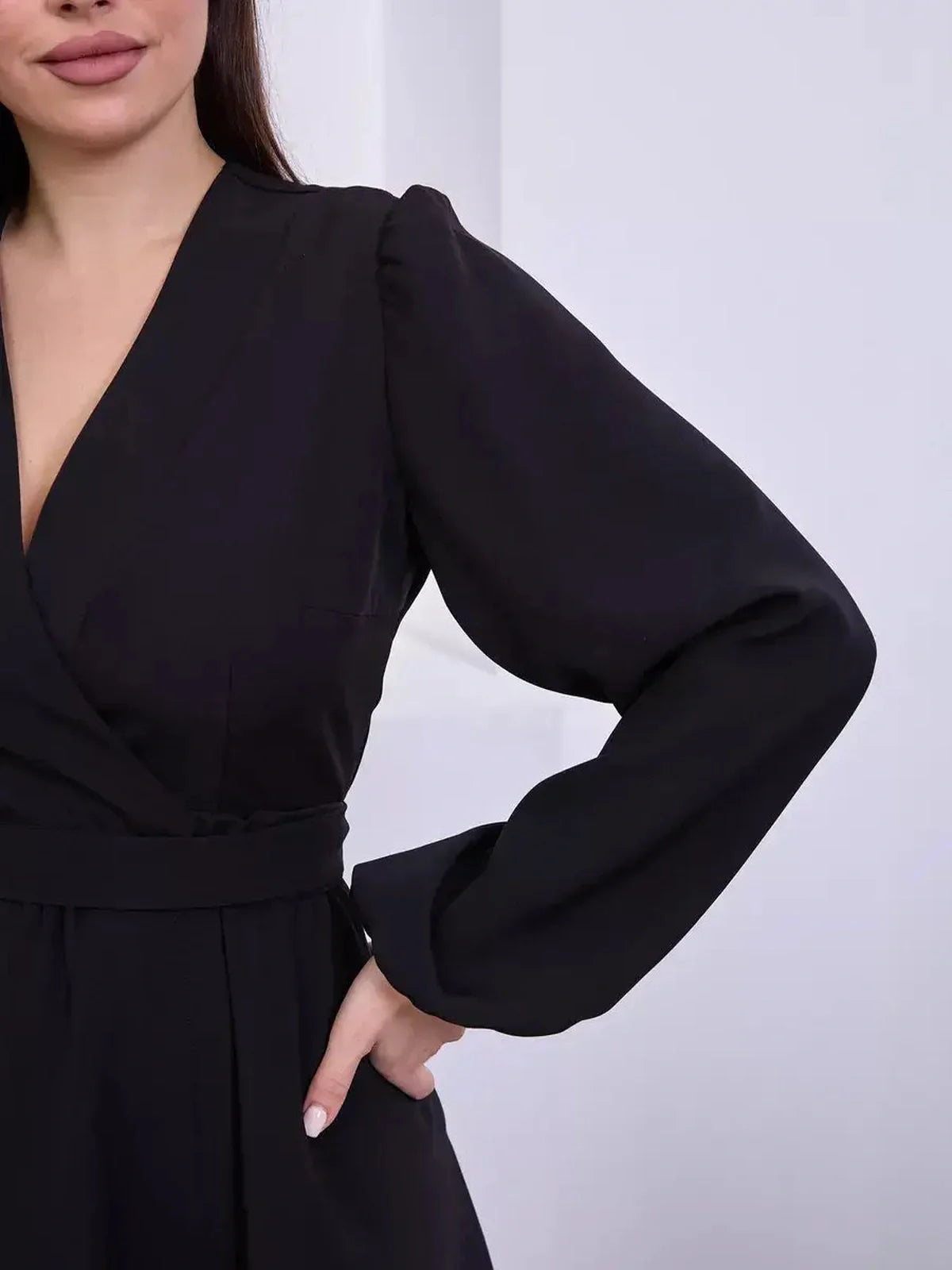 Close-up of a woman in a black mini dress featuring a wrap silhouette and V-neckline, perfect for formal events.