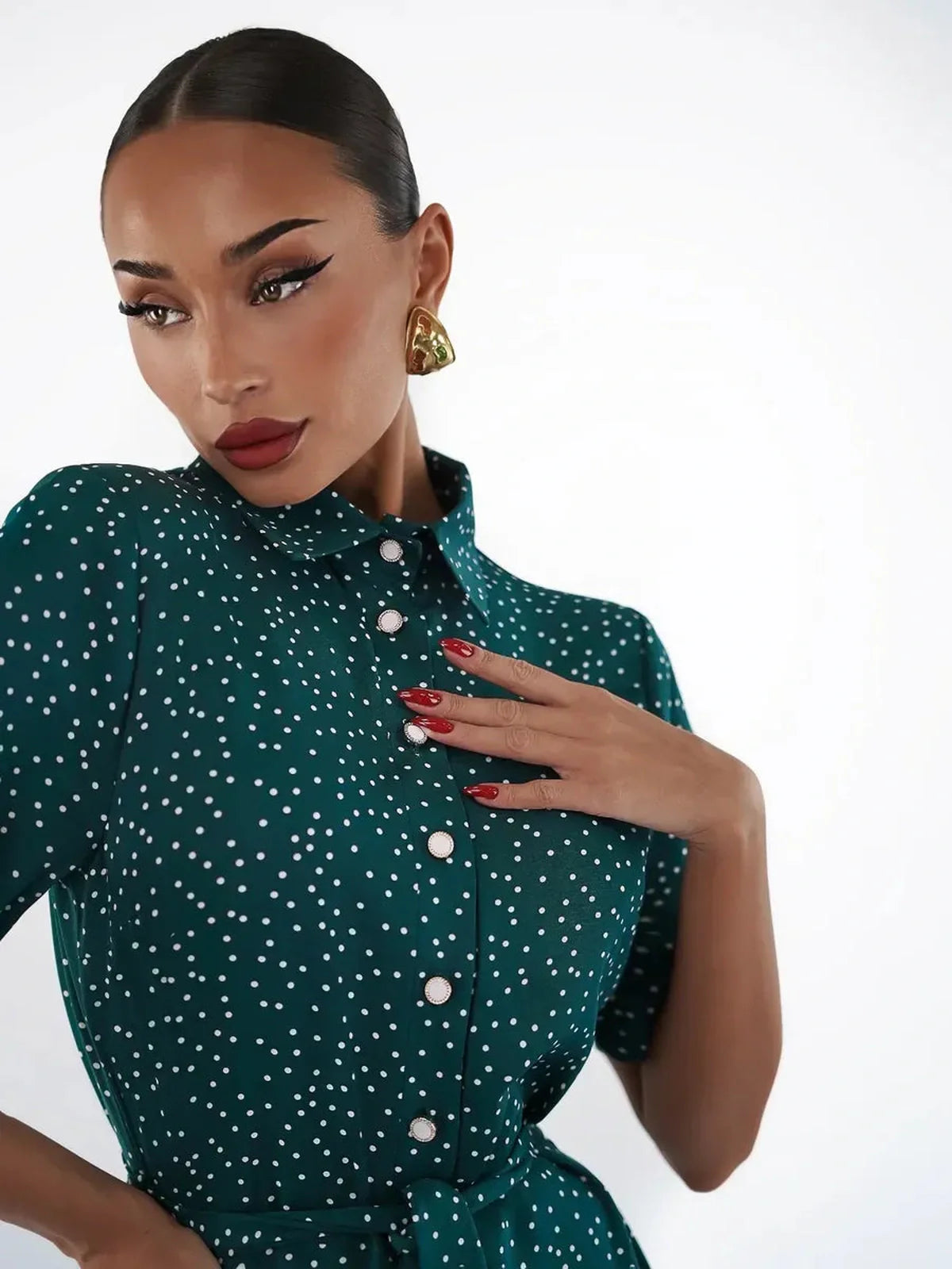 Elegant woman in an emerald dot midi dress, showcasing a sophisticated style with white polka dots and a button-down design.