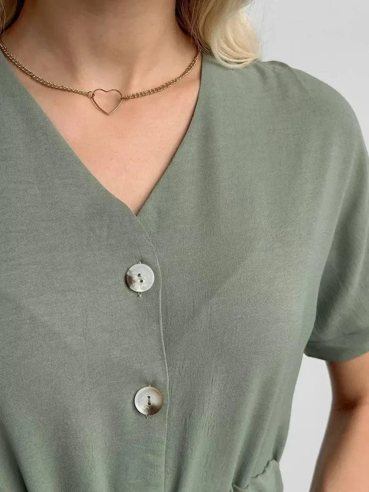 Close-up of a woman wearing a khaki Botany Midi Dress, featuring a V-neckline and decorative buttons.