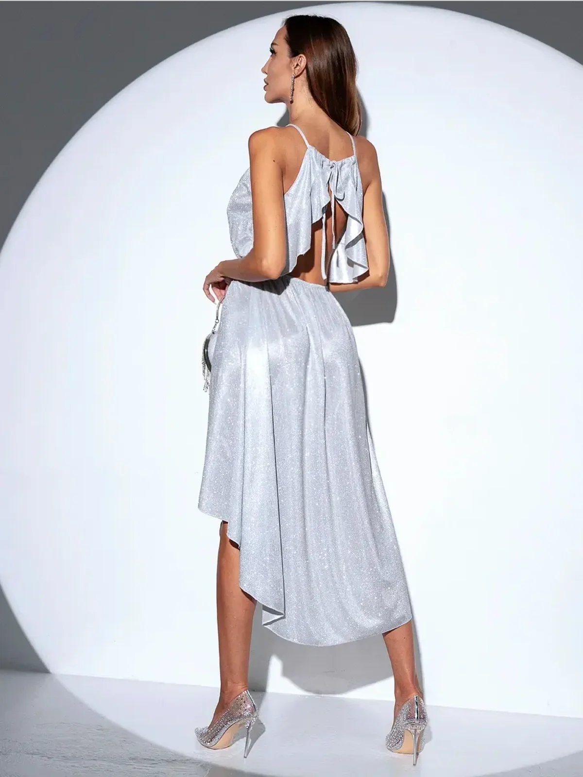 Stylish woman in a Celestial Glow Midi Dress, featuring a sparkling backless design and elegant high-low hem.