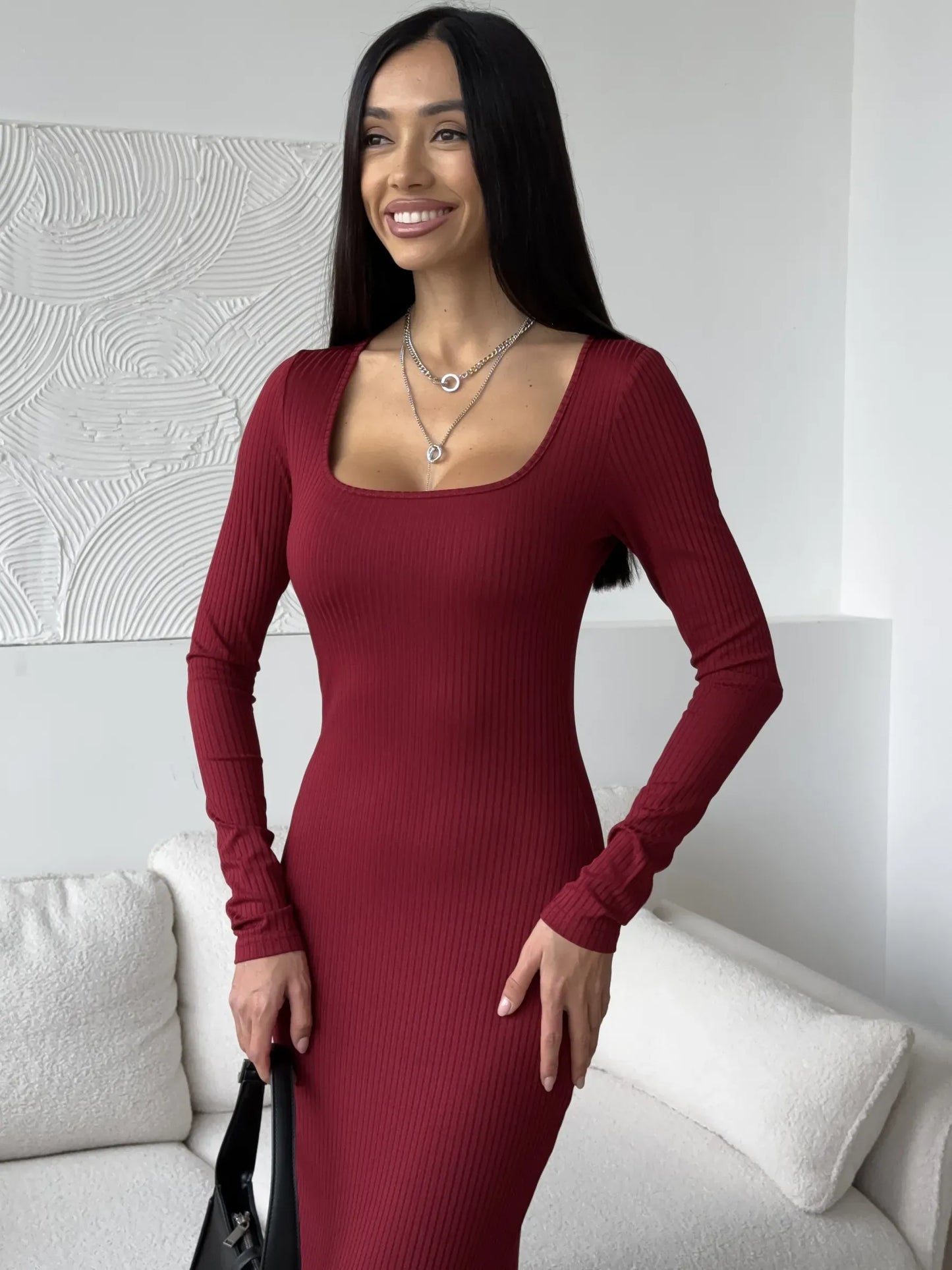Sophisticated woman wearing a ribbed burgundy midi dress with a square neckline and long sleeves.