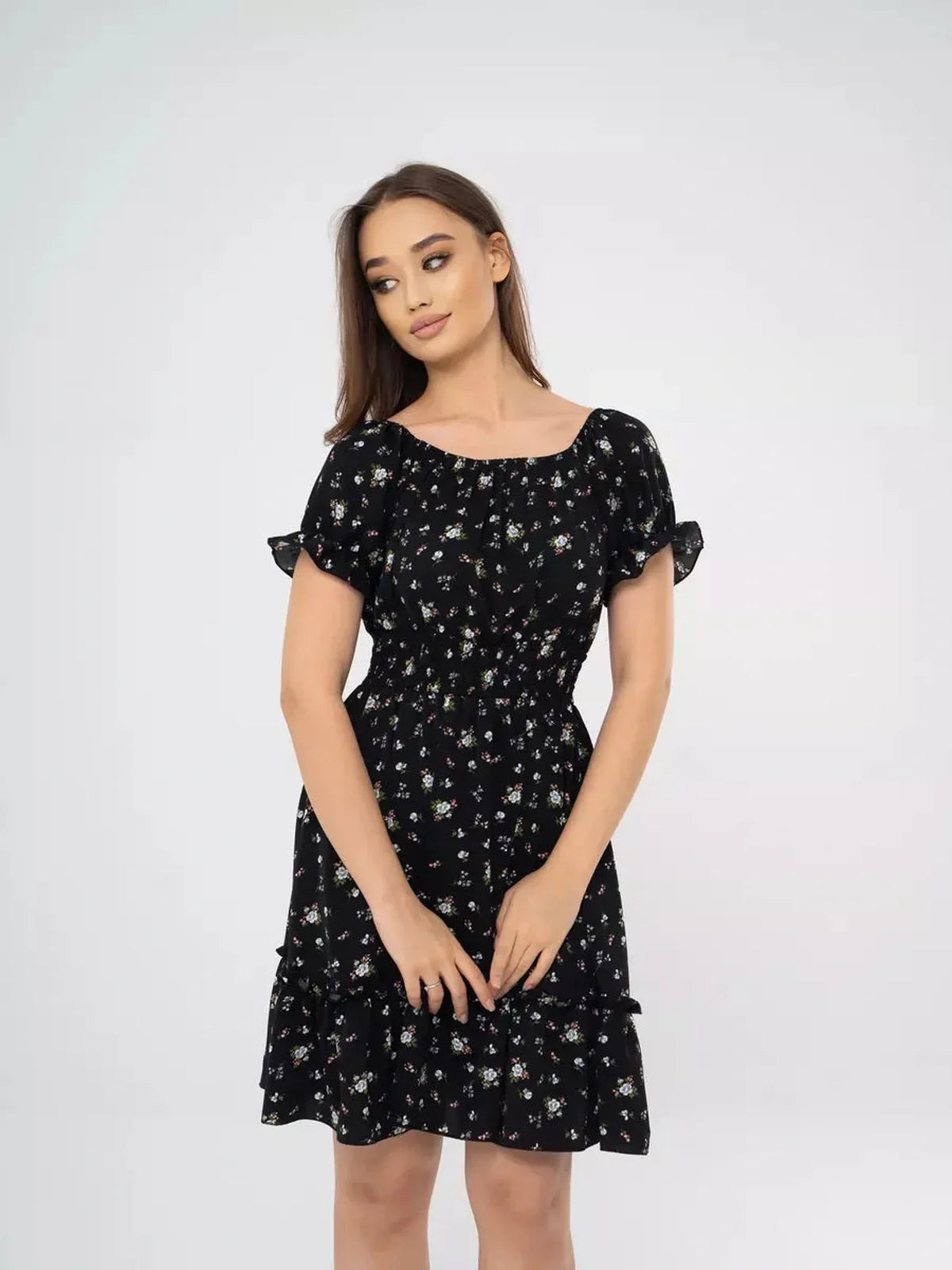 Model wearing the Midnight Bloom black floral mini dress with off-shoulder neckline and tiered skirt, perfect for summer events.