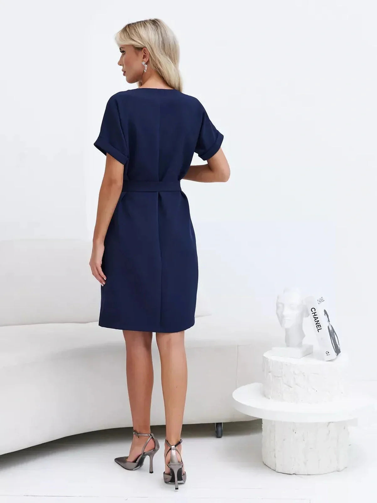 Back view of a woman wearing a Navy Line mini dress, showcasing its structured silhouette and waist-defining belt.