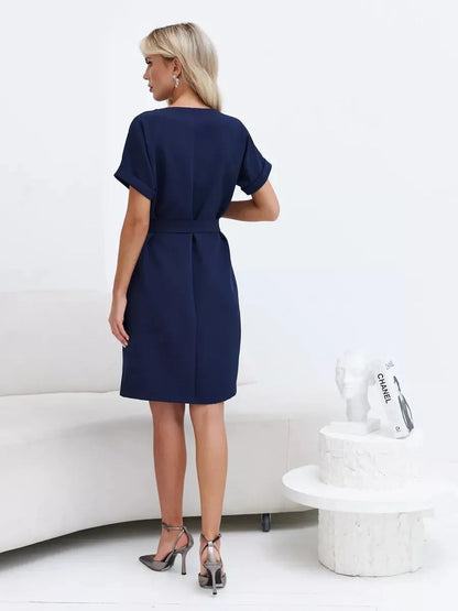 Back view of a woman wearing a Navy Line mini dress, showcasing its structured silhouette and waist-defining belt.