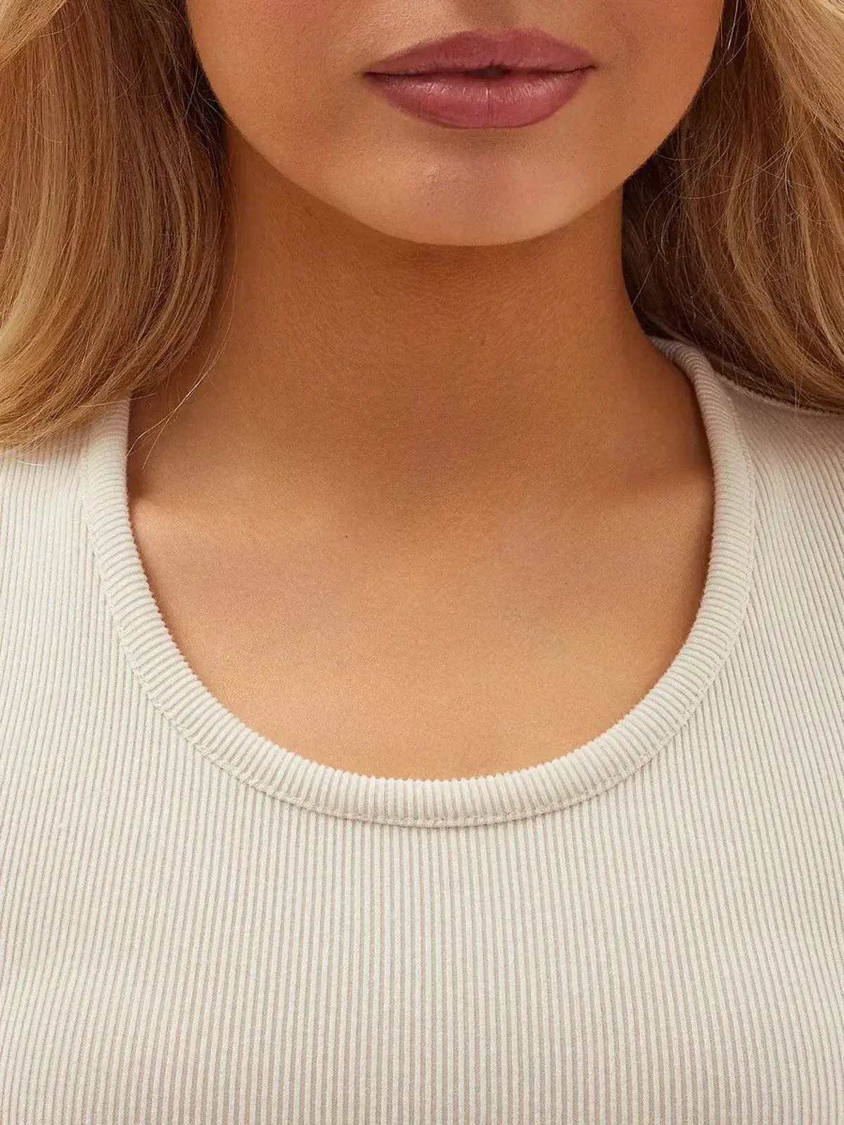 Close-up of a woman wearing a vanilla ribbed dress with a scoop neckline, showcasing an elegant and modern style.