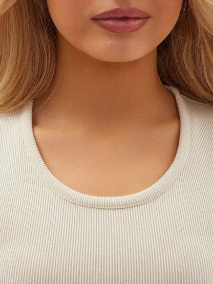 Close-up of a woman wearing a vanilla ribbed dress with a scoop neckline, showcasing an elegant and modern style.