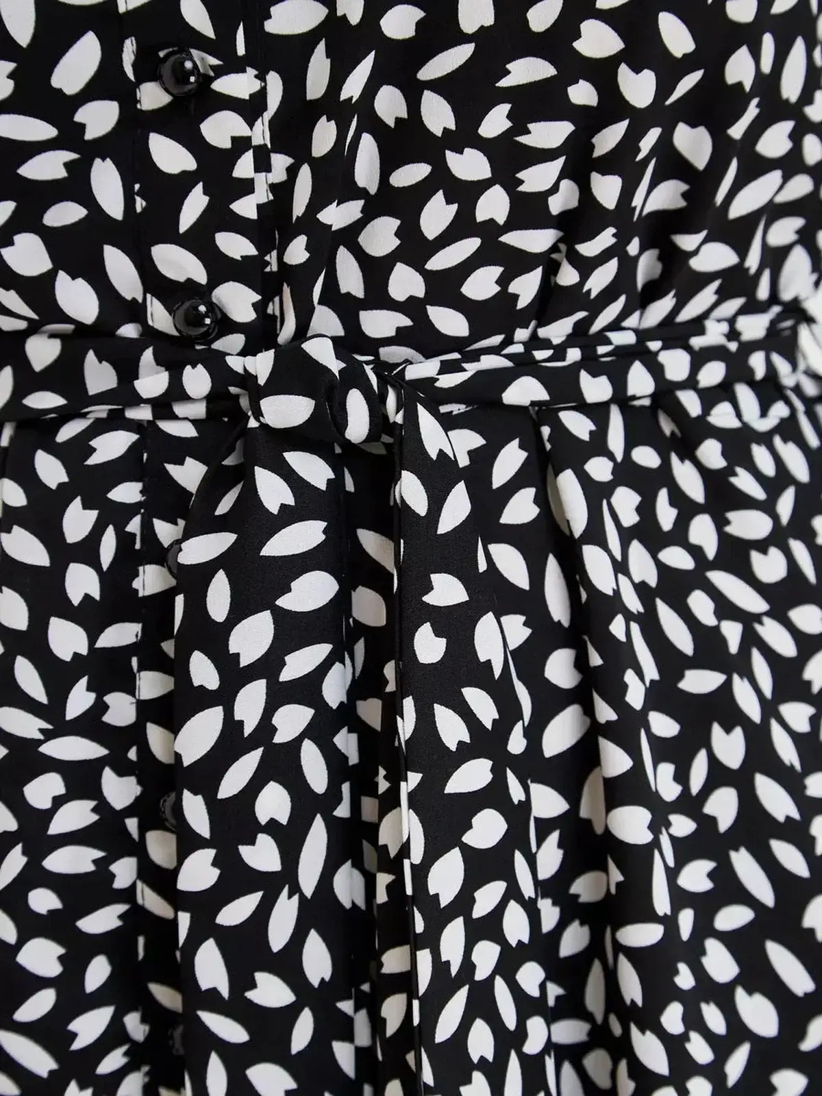 Close-up of Monaco Midi Dress showcasing the black and white print, button details, and waist tie for a flattering silhouette.