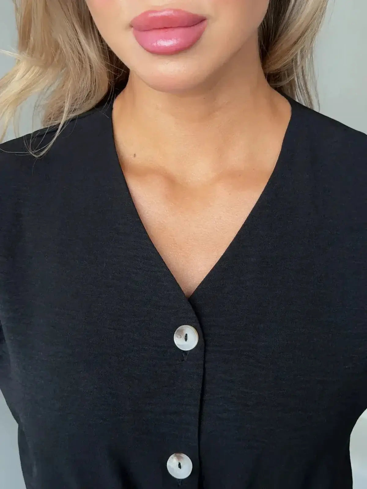 Close-up of the V-neckline and button detail on the Iconic Ease Midi Dress, showcasing its elegant design.