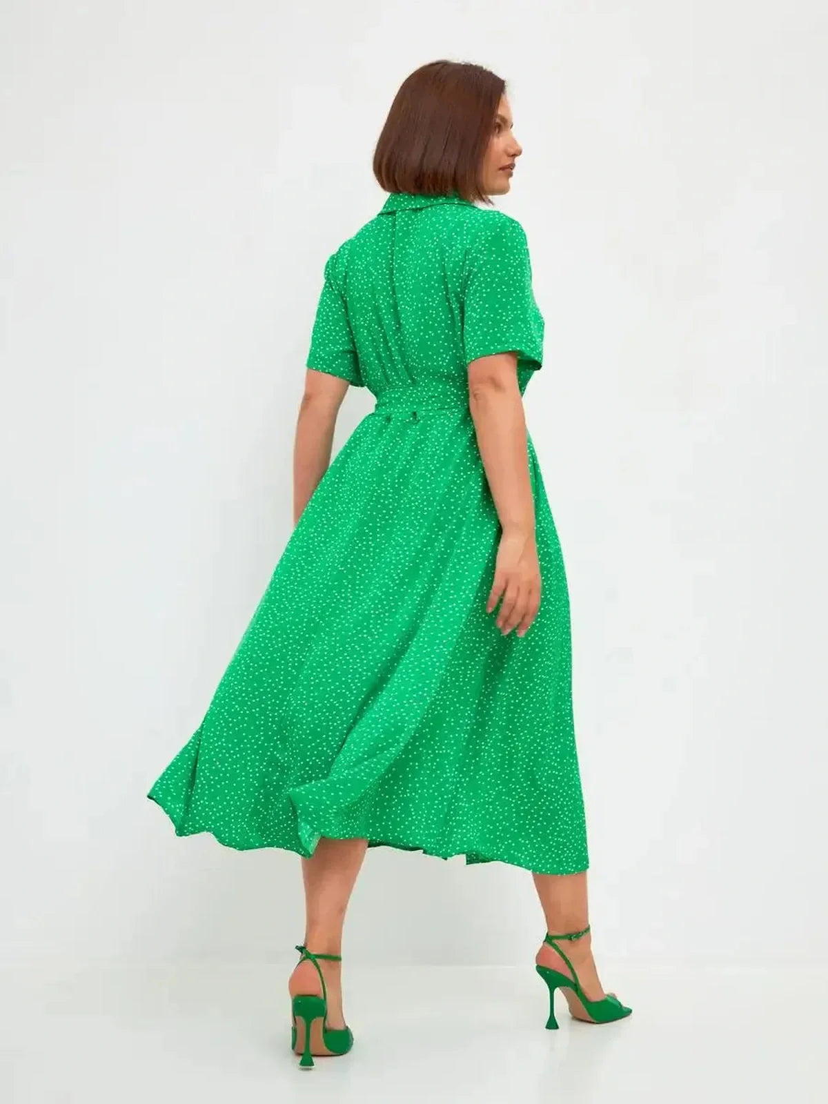 Back view of a vibrant green midi dress with white dots, featuring a tie waist and flowing hemline, perfect for summer occasions.