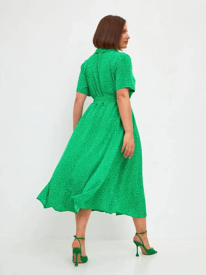Back view of a vibrant green midi dress with white dots, featuring a tie waist and flowing hemline, perfect for summer occasions.