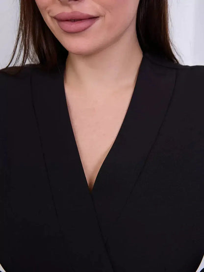 Close-up of a woman wearing a black wrap dress with a V-neckline, highlighting elegant fashion details.