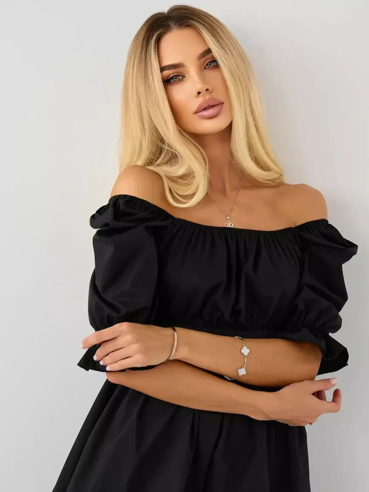Elegant woman in a black off-shoulder mini dress with puff sleeves, perfect for summer and formal occasions.