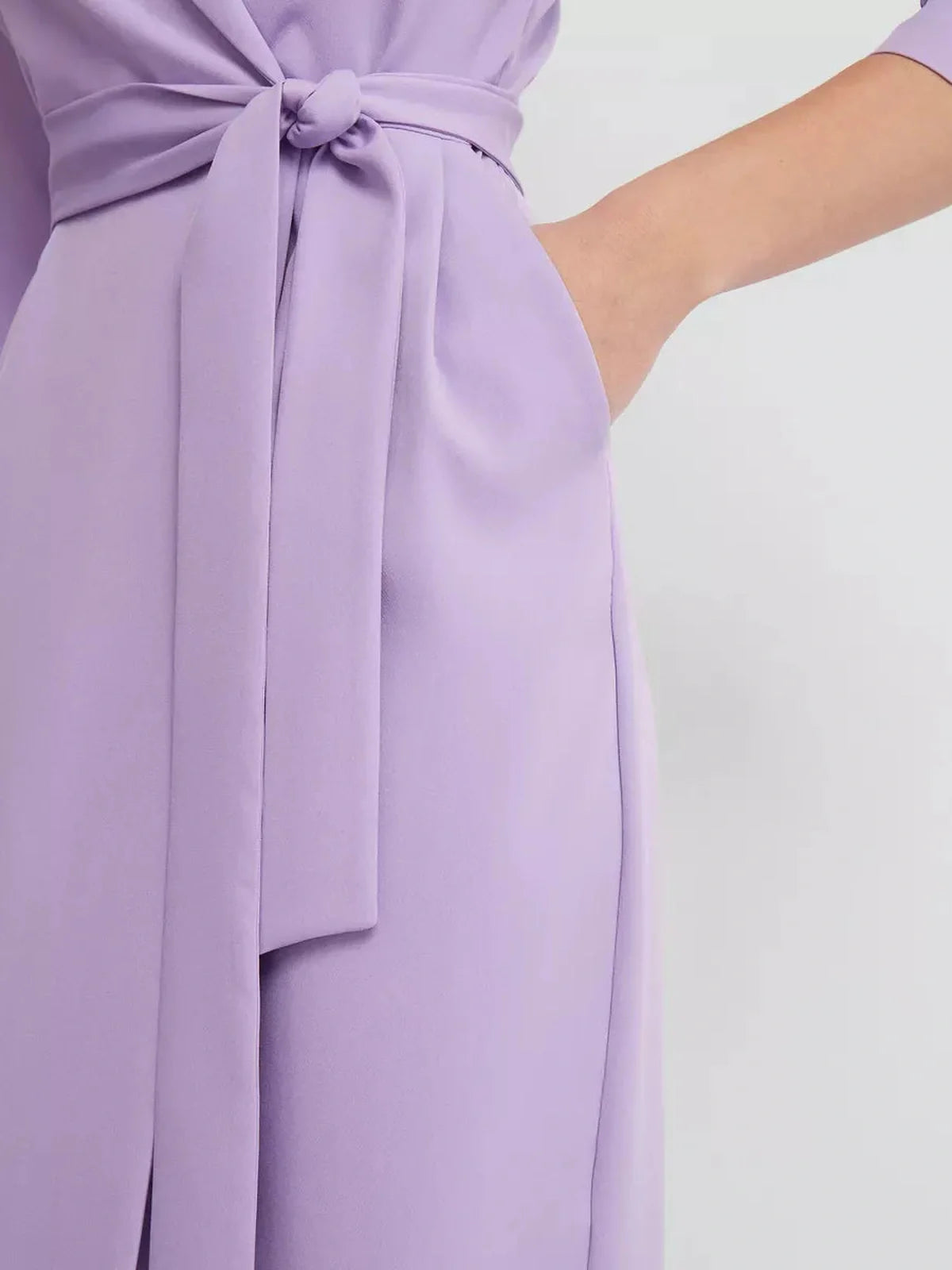 Detail of the Lilac Grace Midi Dress showcasing the elegant knot tie and pocket design in a soft lilac hue.