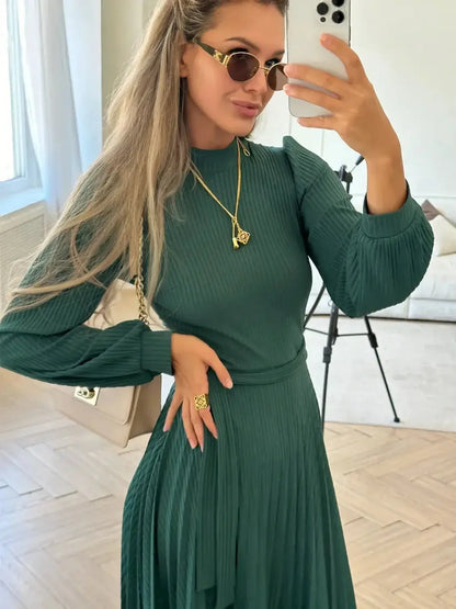 Model wearing the Emerald Poise Midi Dress in green, showcasing its pleated design and ribbed texture, ideal for elegant occasions.
