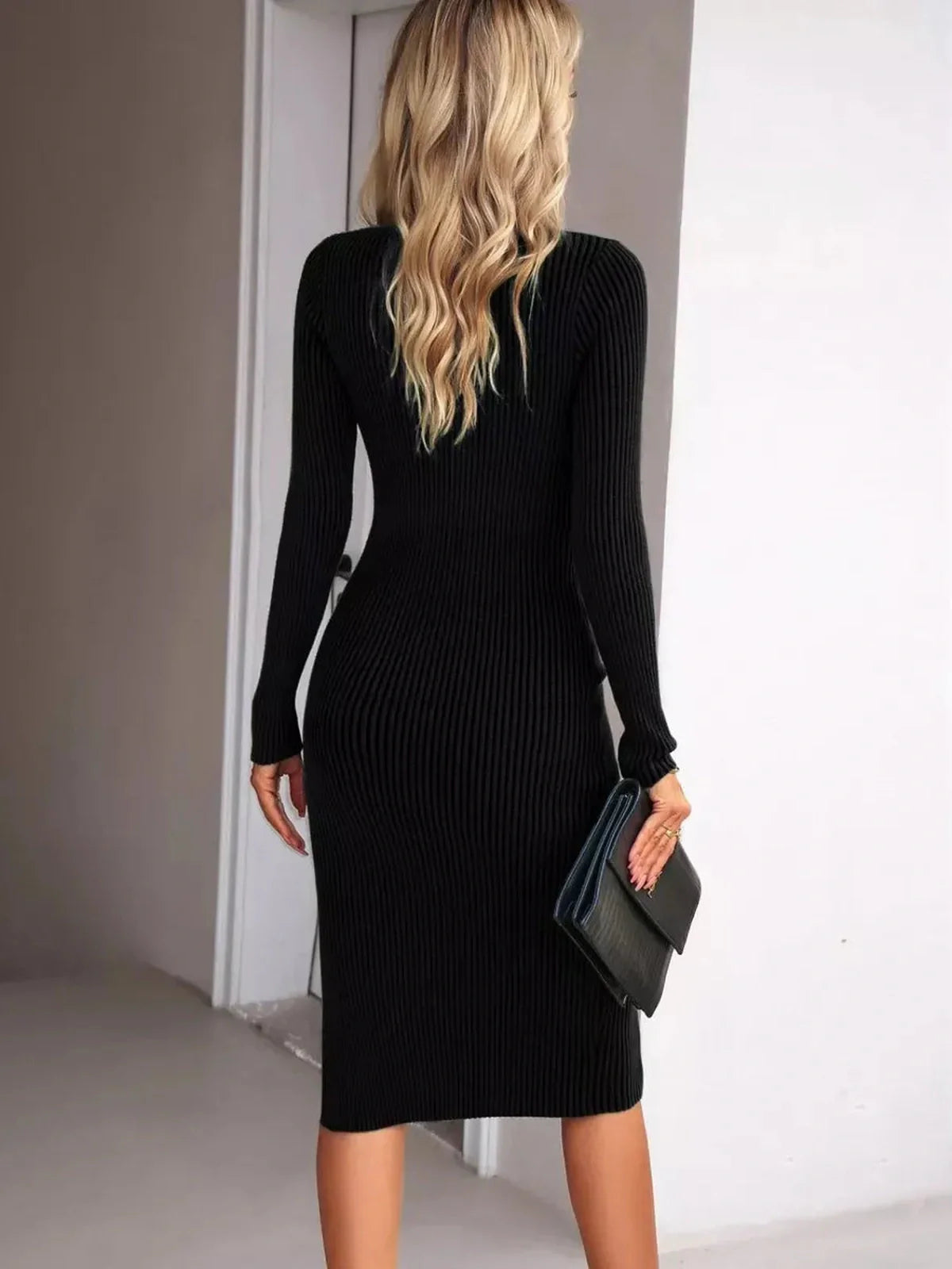 Back view of a woman in a black ribbed midi dress, showcasing a sleek silhouette and elegant fit.
