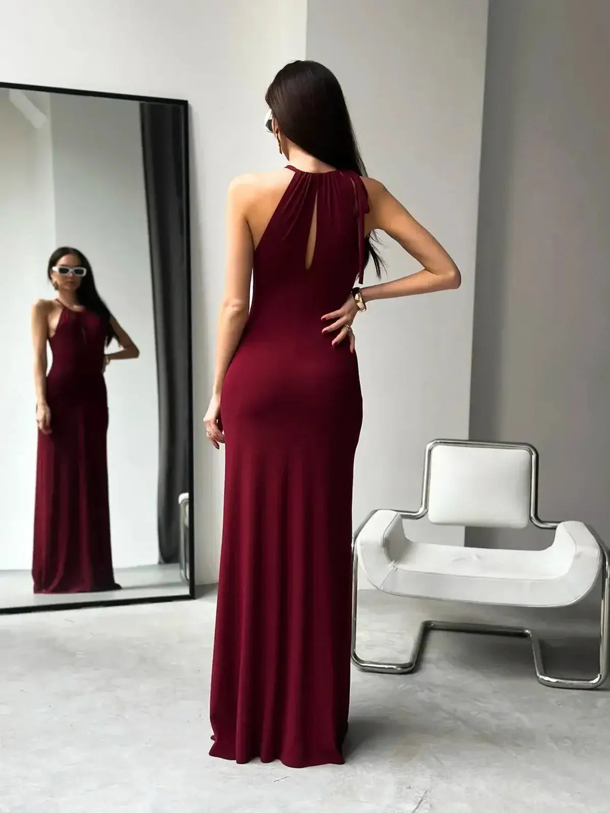 Elegantly draped halter neck maxi dress in burgundy, featuring ruched waist and keyhole detail, perfect for weddings or formal events.