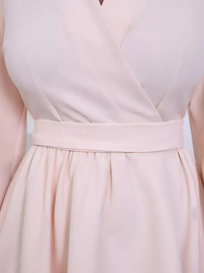 Close-up of a champagne-toned mini dress with a soft V-neck wrap, long puff sleeves, and a flattering fit-and-flare silhouette.