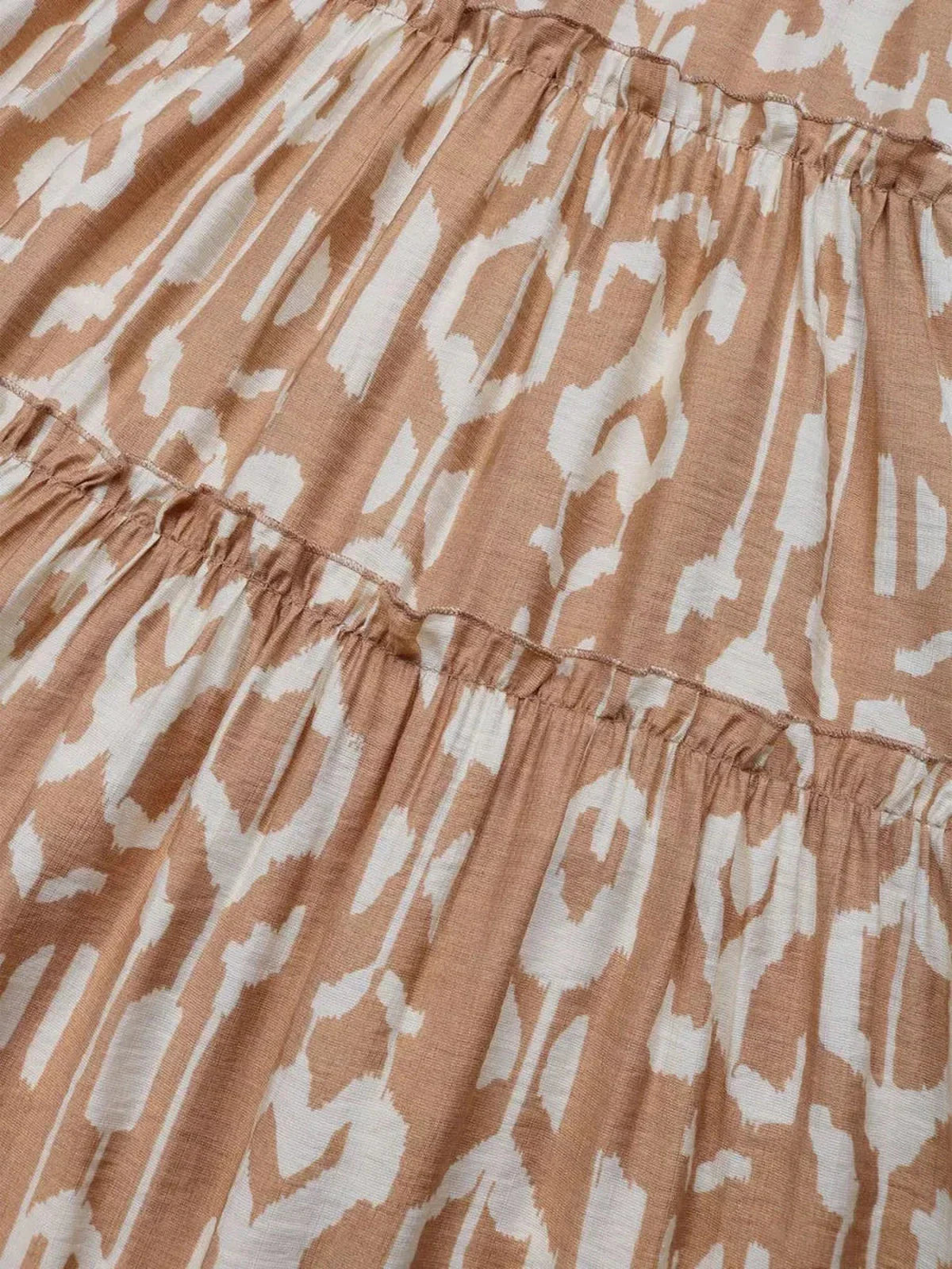 Detail of the Nomad Tiered Midi Dress showcasing a bohemian geometric print in light brown and white fabric.
