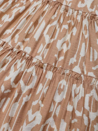 Detail of the Nomad Tiered Midi Dress showcasing a bohemian geometric print in light brown and white fabric.