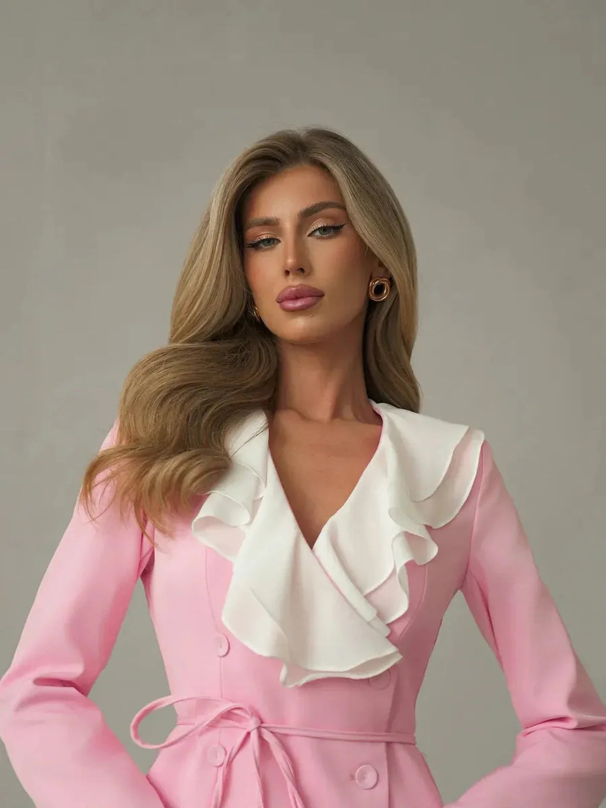 Elegant model showcasing the Rose Cascade mini dress with dramatic white ruffle neckline in blush pink.