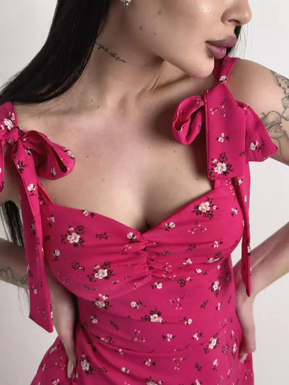 Close-up of a woman wearing a vibrant pink floral midi dress with sweetheart neckline and adjustable shoulder ties.