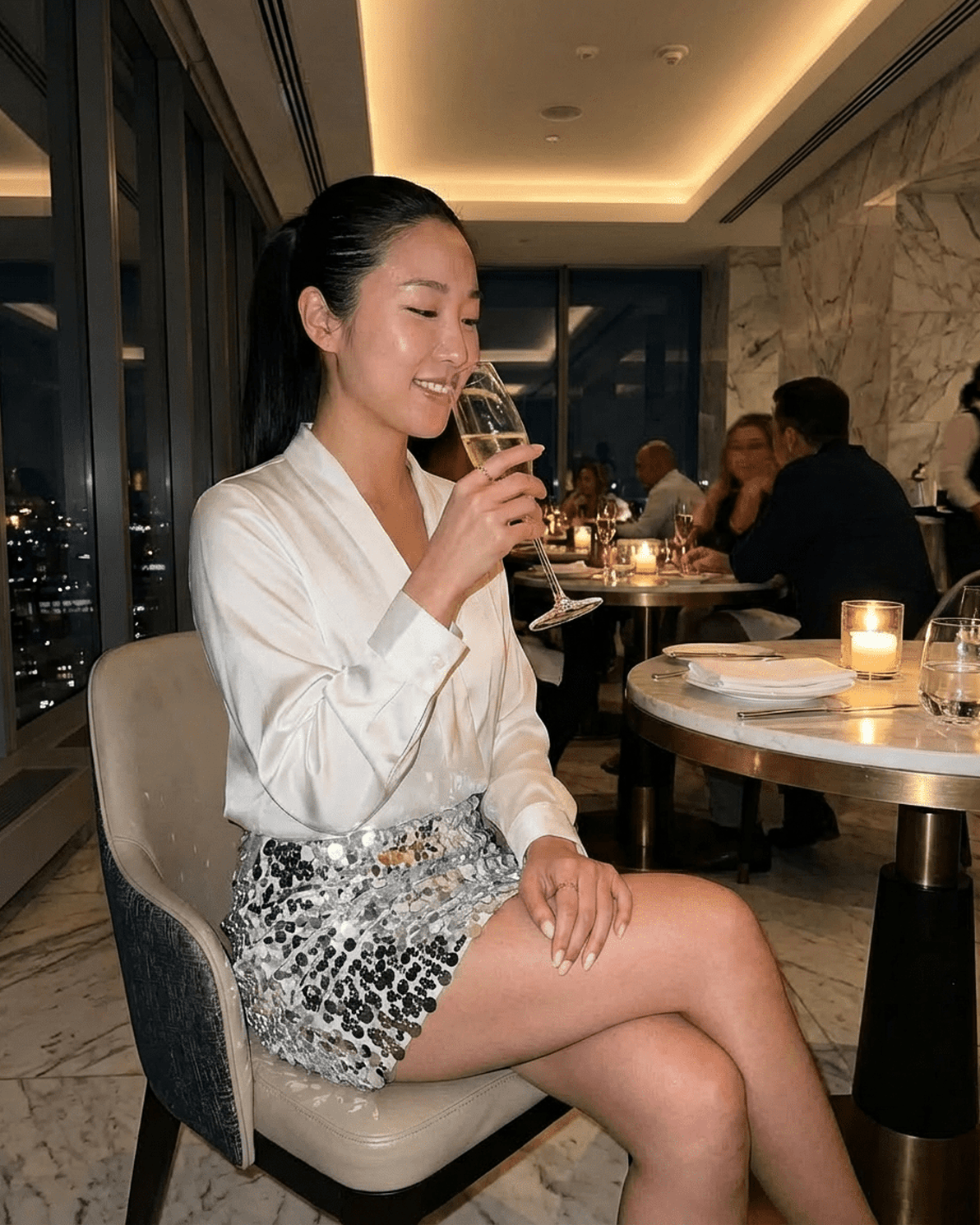 Celeste Mini Skirt worn by a woman enjoying a drink in an elegant restaurant setting, showcasing Slimona brand glamour.