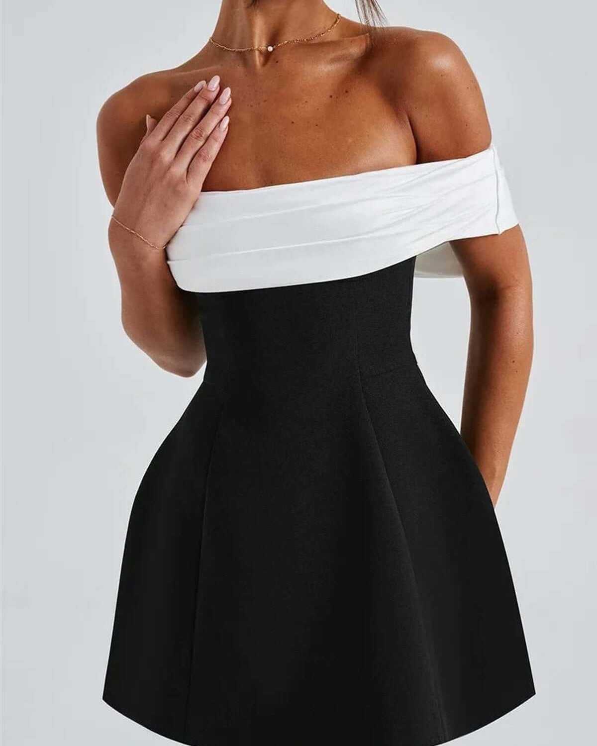 Elegant black and white off-shoulder mini dress featuring an oversized bow, perfect for wedding guests or parties.