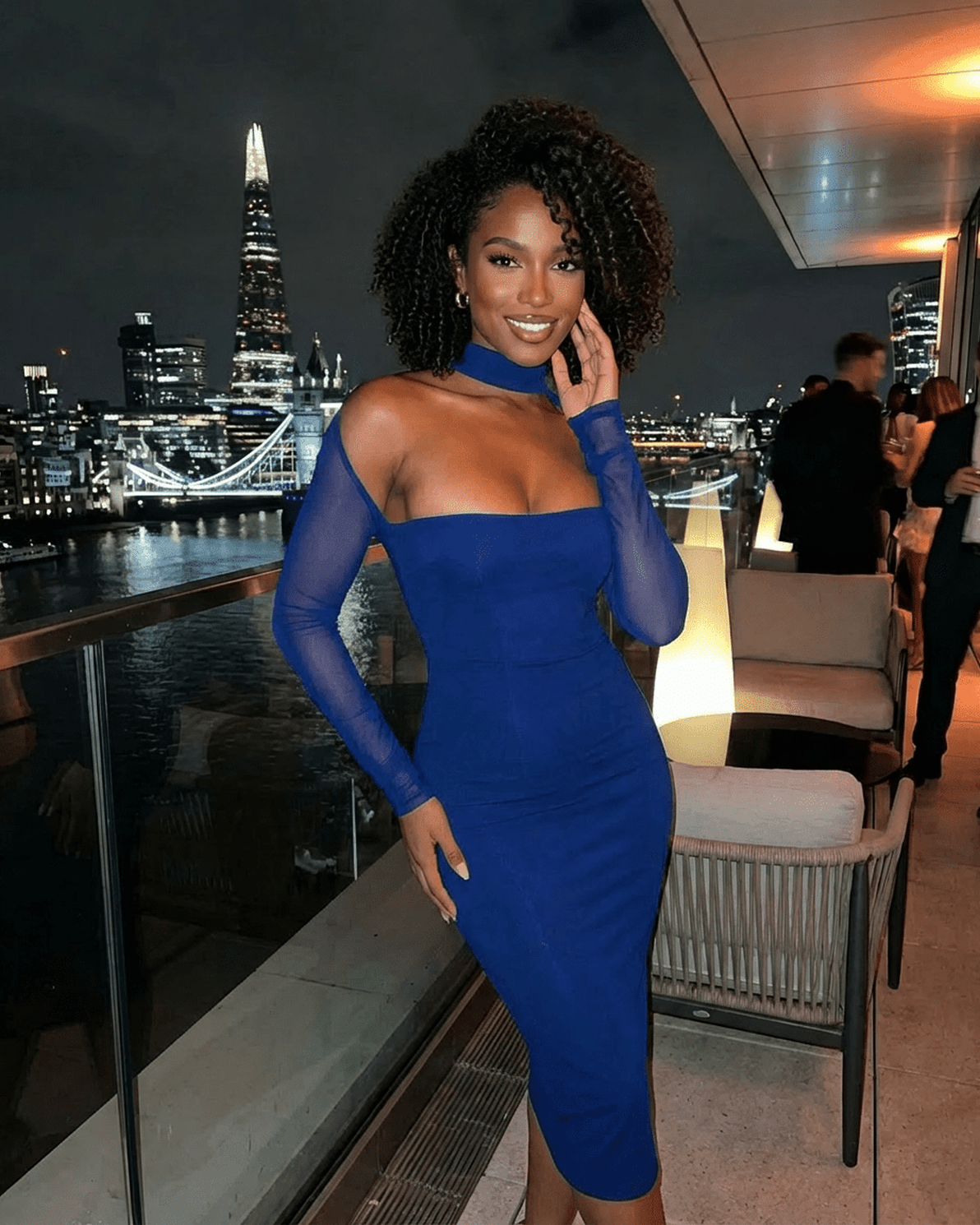 Model wearing the Arden Blue Dress by Slimona, showcasing a chic bodycon design against a city skyline.