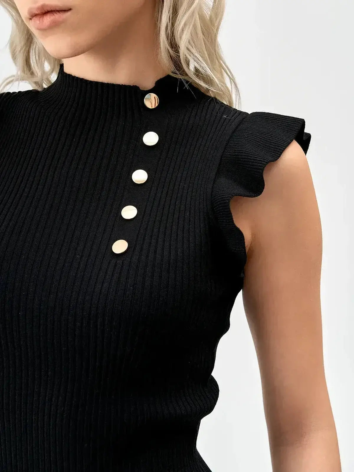 Close-up of a stylish black ribbed mini dress featuring a high neckline and gold button detailing.